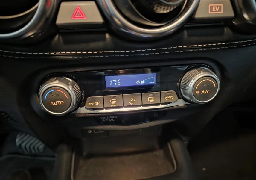 Gros plan sur la console centrale du Nissan Juke 2024, montrant la climatisation automatique avec affichage digital à 17,6°C.