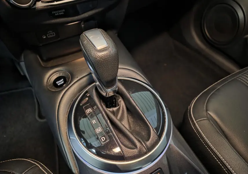 Gros plan sur le levier de vitesses cuir noir de la Nissan Juke 1.6 Hybrid 2024 avec bouton Start/Stop visible.