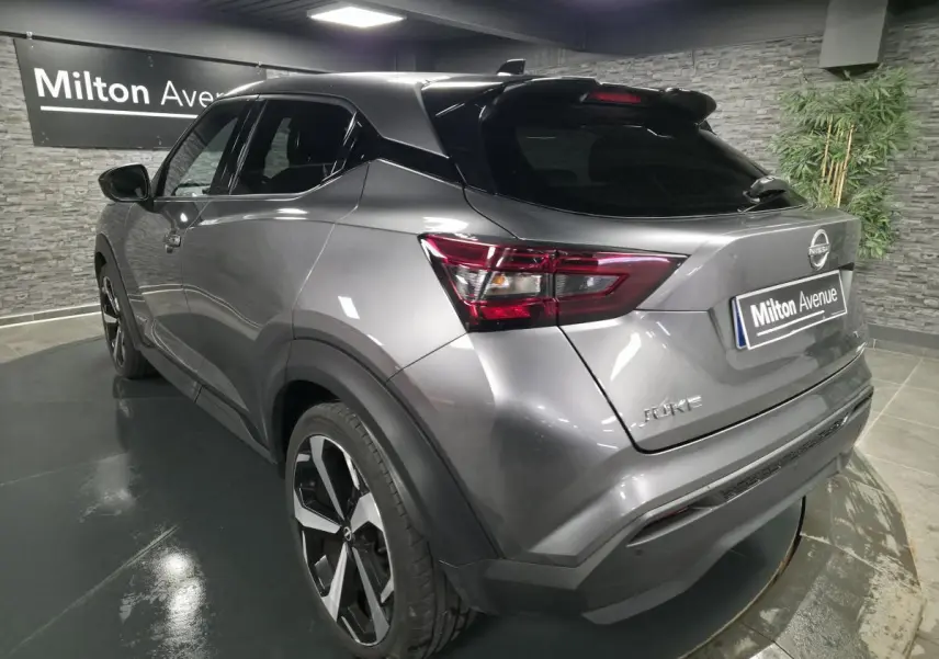 Nissan Juke gris métallisé en 3/4 arrière droit, avec jantes alliage noires et toit noir brillant.