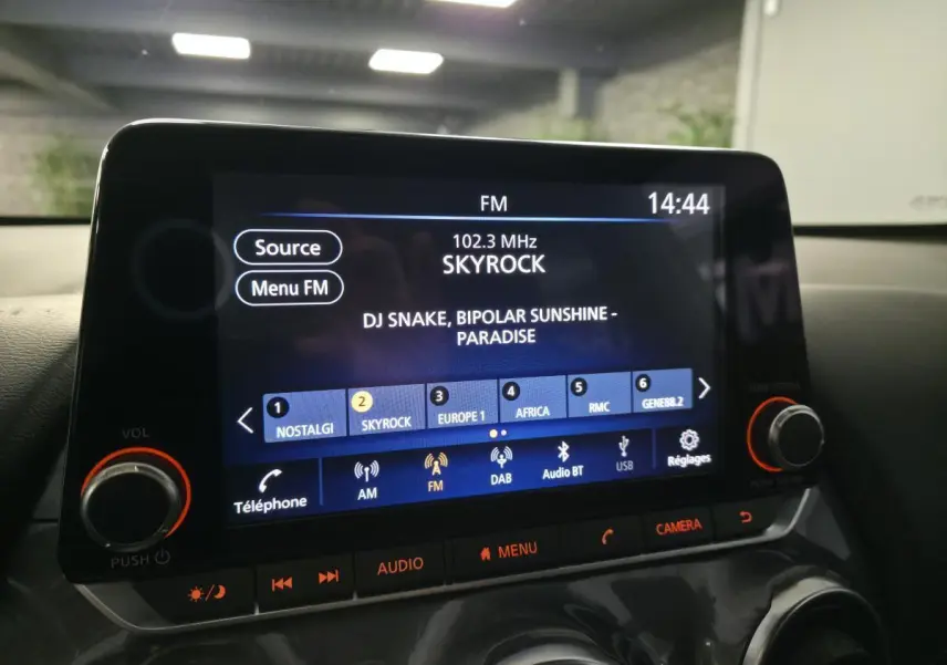 Écran tactile central du Nissan Juke 2024 affichant la radio FM Skyrock, avec commandes audio et bouton caméra.