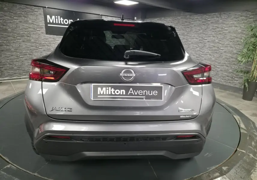 Vue arrière d'un Nissan Juke gris métallisé 2024 avec logo Hybrid et feux arrière LED distinctifs.