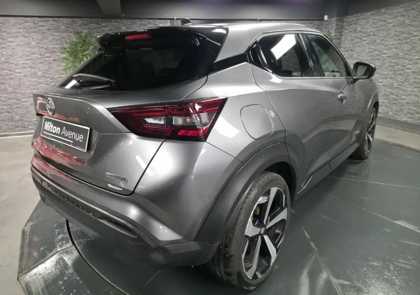 Vue 3/4 arrière droite du Nissan Juke 1.6 Hybrid gris métallisé avec jantes alliage 19 pouces et toit noir.