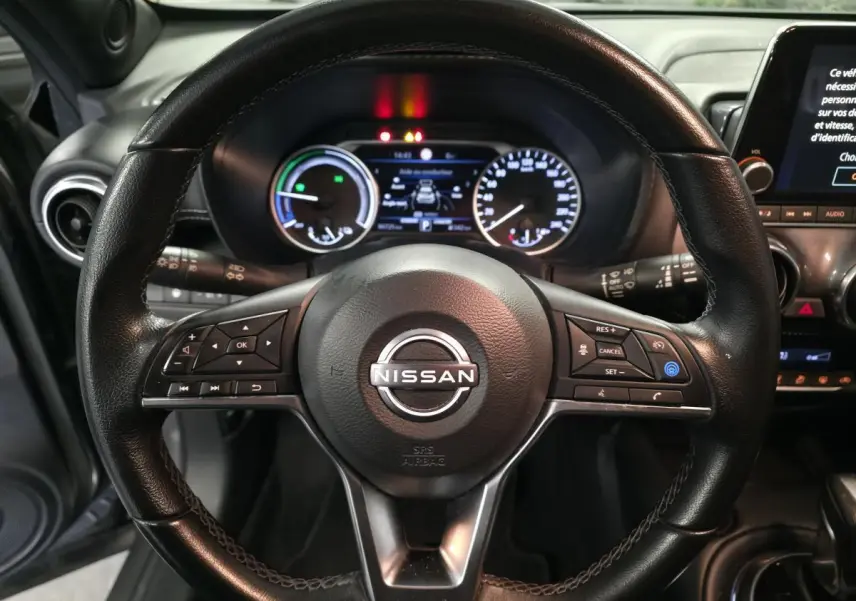 Vue rapprochée du volant cuir noir de la Nissan Juke 2024 avec commandes intégrées et tableau de bord numérique.