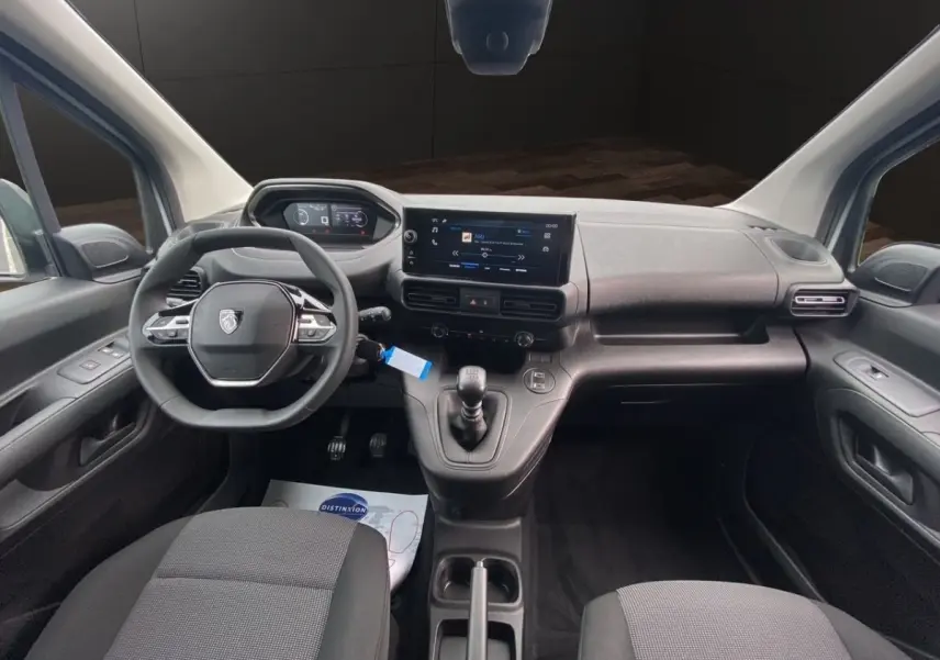 Vue intérieure avant du Peugeot Partner blanc 2024, tableau de bord avec écran tactile et volant multifonctions.