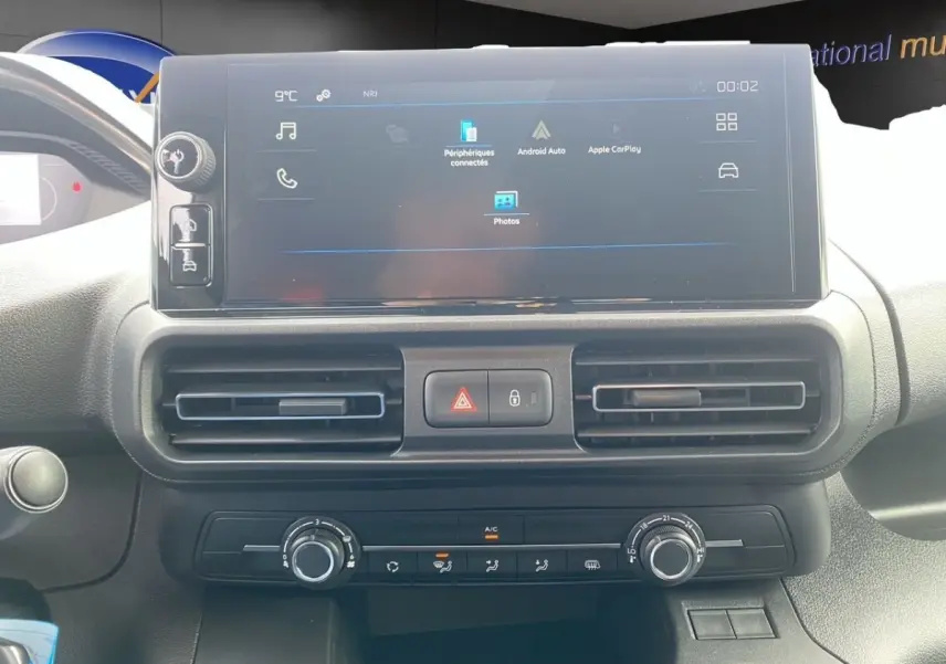 Vue rapprochée du tableau de bord du Peugeot Partner 2024 avec écran tactile central et commandes de climatisation.