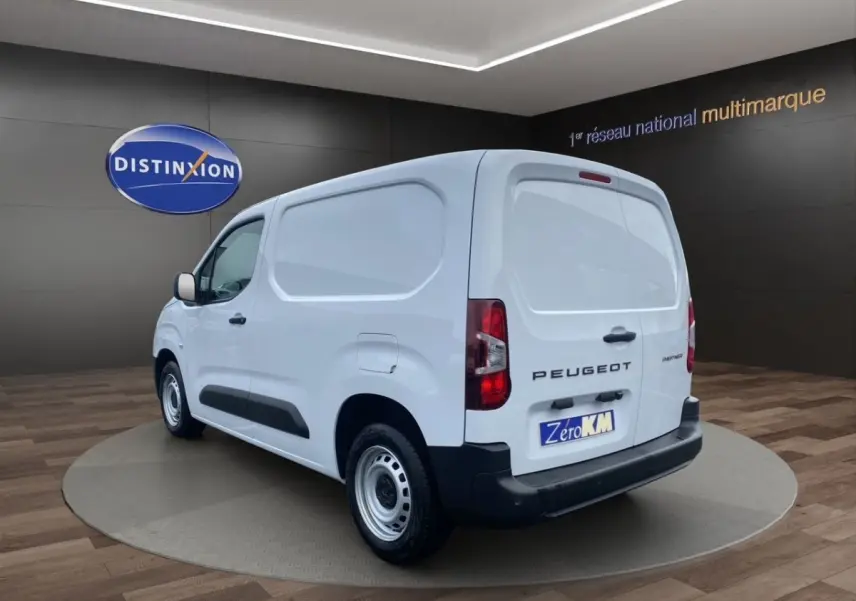 Vue 3/4 arrière droite d’un Peugeot Partner blanc, fourgon utilitaire avec pare-chocs noir et jantes acier.