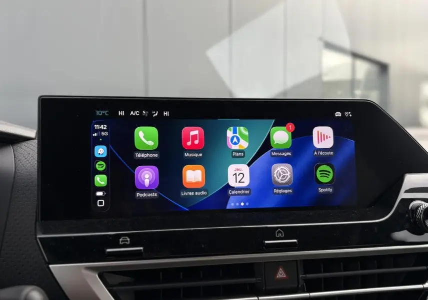 Écran tactile central de la Citroën C4 Hybrid 2025 affichant Apple CarPlay avec icônes colorées, ambiance intérieure moderne.