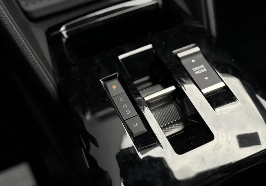 Gros plan sur la console centrale noire brillante de la Citroën C4 Hybrid 145 avec sélecteur de boîte auto et bouton Drive Mode.
