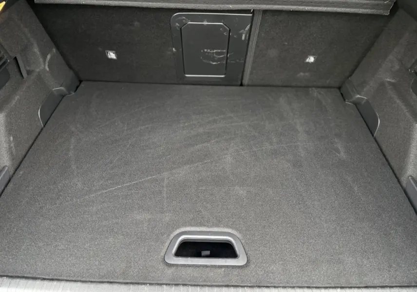 Vue intérieure du coffre spacieux et propre de la Citroën C4 Hybrid 2025 en gris Mercury, avec trappe d'accès au fond.