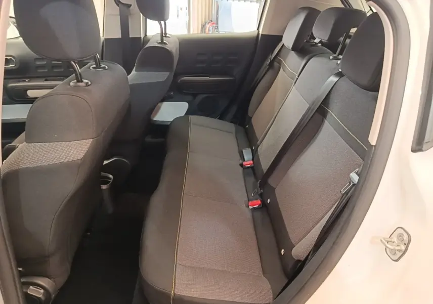 Vue intérieure côté droit de la banquette arrière grise du Citroën C3 blanc, avec appuie-têtes et ceintures visibles.