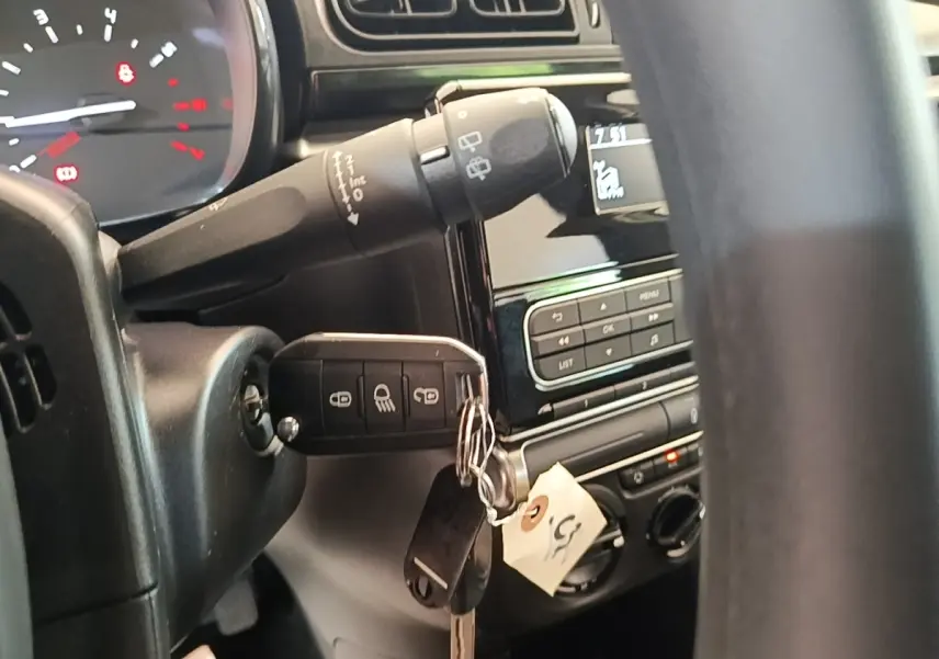 Vue rapprochée de l’intérieur côté conducteur d’une Citroën C3 blanche, clé insérée dans le contacteur avec tableau de bord partiel.