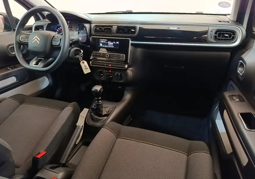 Vue intérieure avant droite du tableau de bord noir brillant et des sièges gris foncé de la Citroën C3 PureTech 110.