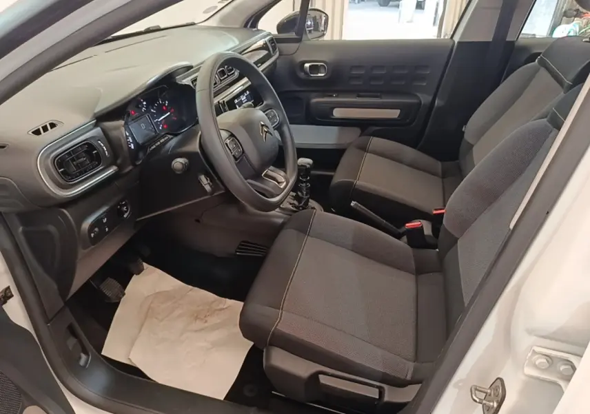 Intérieur de la Citroën C3 blanc, vue côté conducteur, montrant sièges gris et tableau de bord moderne.