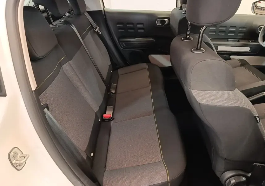 Vue intérieure côté arrière droit de la Citroën C3 blanche 2019, montrant la banquette arrière en tissu gris et noir.