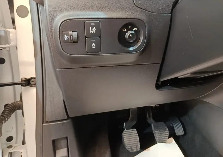 Vue intérieure côté conducteur montrant les commandes d'éclairage et les pédales d'une Citroën C3 blanche de 2019.
