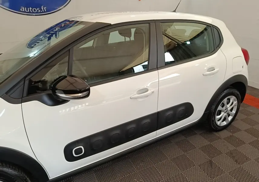 Vue latérale droite d'une Citroën C3 blanche avec protections latérales noires et rétroviseur noir brillant.