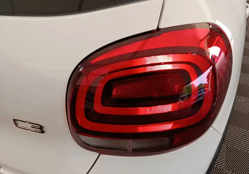 Gros plan sur le feu arrière droit rouge d'une Citroën C3 blanche, modèle 2019, avec logo C3 visible.