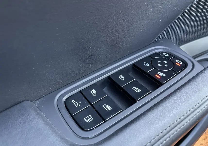 Gros plan sur les commandes de lève-vitres et rétroviseurs côté conducteur d’un Porsche Cayenne gris Kerguelen 2018.