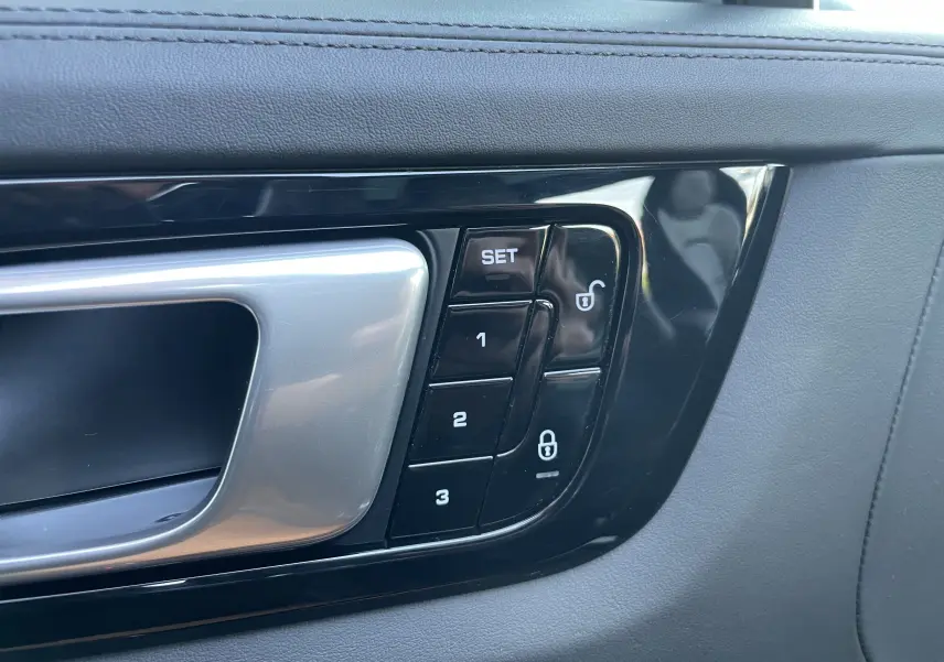 Gros plan sur la poignée intérieure côté gauche du Porsche Cayenne E-Hybrid 2018 avec boutons de réglage mémoire et verrouillage.