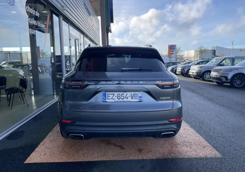 Vue arrière d’un Porsche Cayenne E-Hybrid 462 BVA gris Kerguelen, avec feux allongés et double sortie d’échappement.