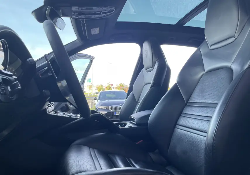 Vue intérieure côté conducteur du Porsche Cayenne E-Hybrid 2018 avec sièges cuir noirs et toit panoramique.