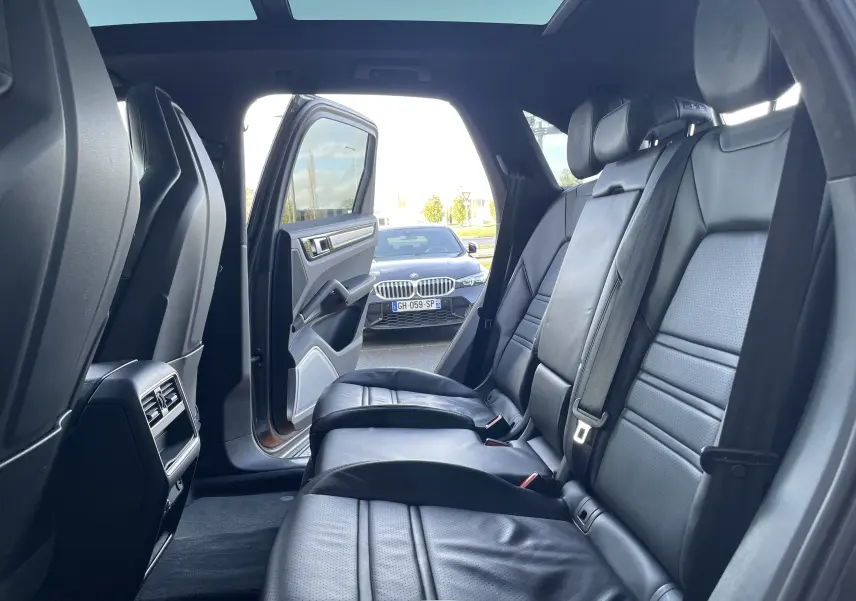 Vue intérieure arrière du Porsche Cayenne E-Hybrid 2018 avec portes ouvertes et sièges en cuir noir visibles.