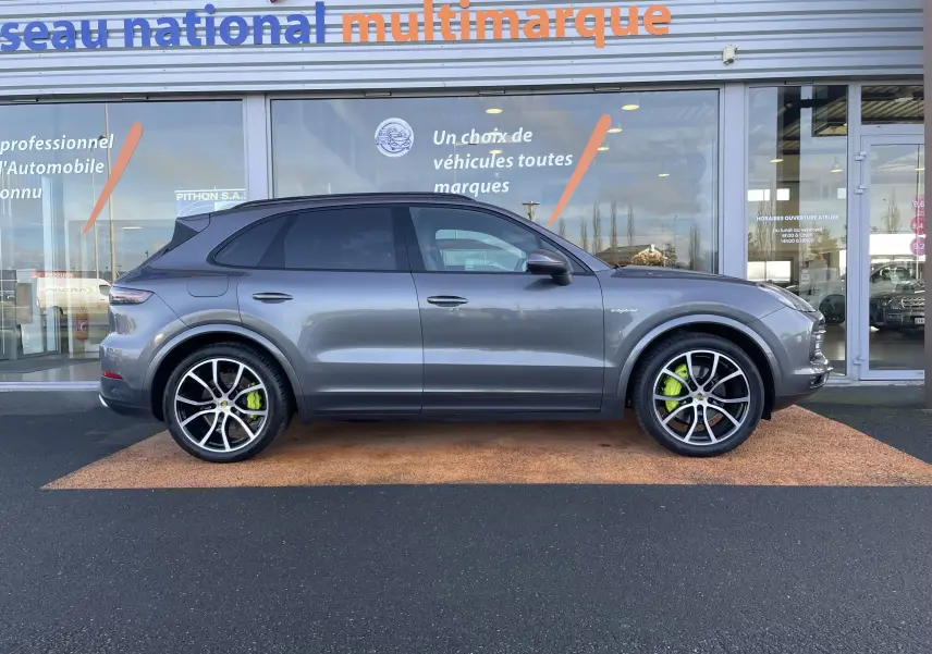 Vue de profil droit d’un Porsche Cayenne E-Hybrid 462 BVA gris Kerguelen avec étriers de frein verts visibles.
