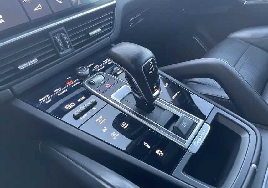 Vue rapprochée de la console centrale du Porsche Cayenne E-Hybrid 2018 avec levier de vitesse et commandes tactiles en noir brillant.