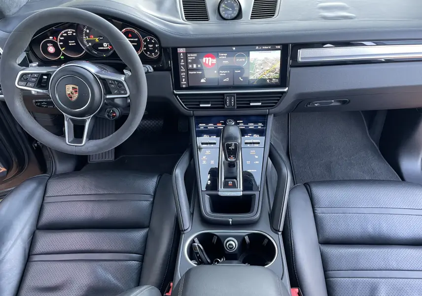 Vue intérieure frontale du Porsche Cayenne E-Hybrid 2018 avec tableau de bord numérique et sellerie cuir noire.
