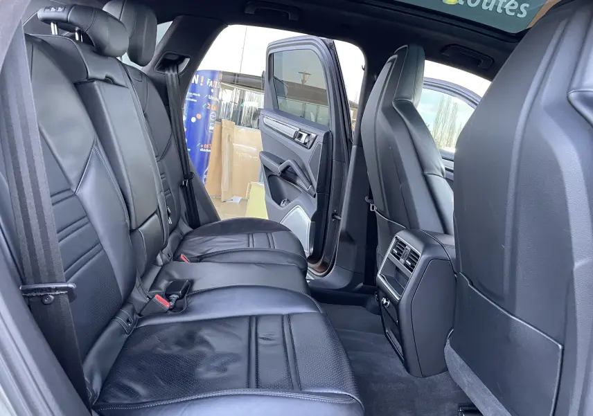 Vue intérieure côté gauche sur les sièges arrière en cuir noir du Porsche Cayenne E-Hybrid 2018 avec porte ouverte.