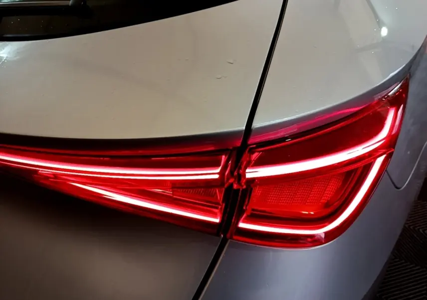 Gros plan sur le feu arrière droit rouge allumé du SEAT LEON gris foncé, soulignant la ligne de coffre.