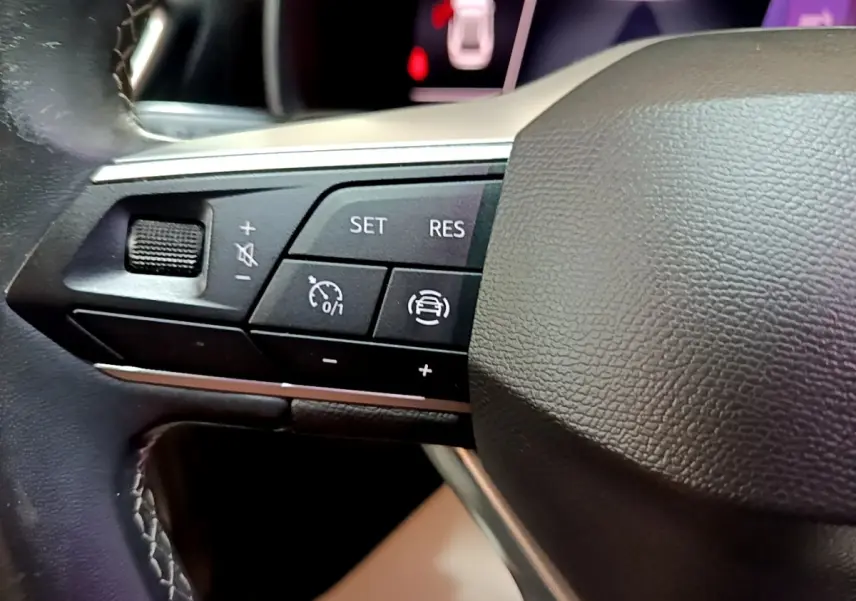 Gros plan sur les commandes de régulateur de vitesse au volant cuir noir du SEAT Leon gris foncé 2022.