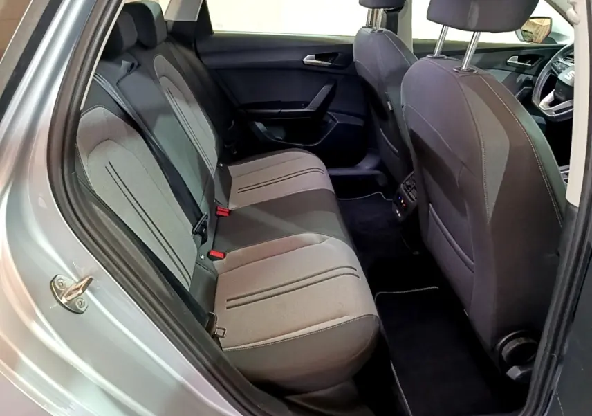 Vue intérieure côté gauche sur la banquette arrière grise du SEAT LEON 2022, avec sièges tissu et détails noirs.