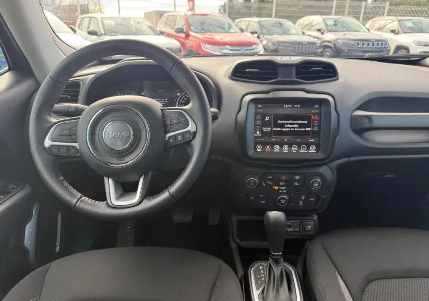 Vue intérieure frontale du tableau de bord et volant noir du Jeep Renegade 2023 avec écran tactile et levier de boîte auto.