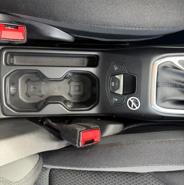 Vue plongeante sur la console centrale noire du Jeep Renegade 2023, avec porte-gobelets et bouton frein de stationnement.