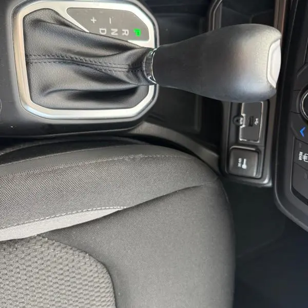 Vue rapprochée de la commande de boîte automatique noire et du siège conducteur en tissu gris du Jeep Renegade 2023.