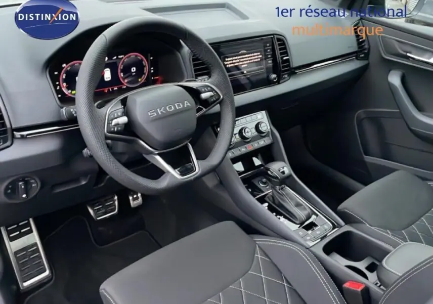 Intérieur avant de la Skoda Karoq 2025 argent, vue du poste de conduite avec volant multifonctions et écran tactile central.