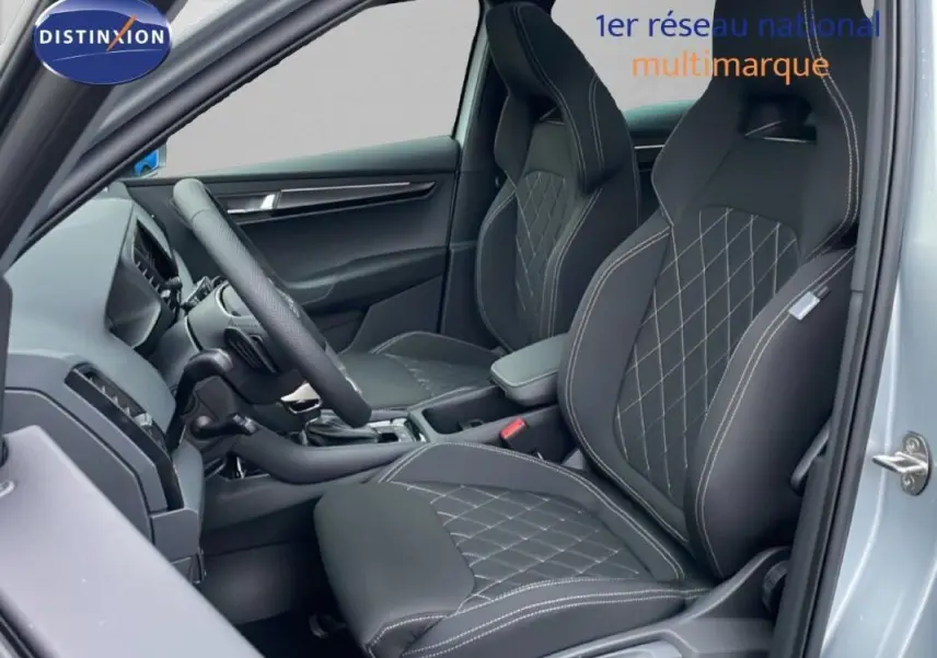 Vue intérieure côté conducteur du Skoda Karoq argent, mettant en valeur les sièges sport noirs avec surpiqûres blanches.