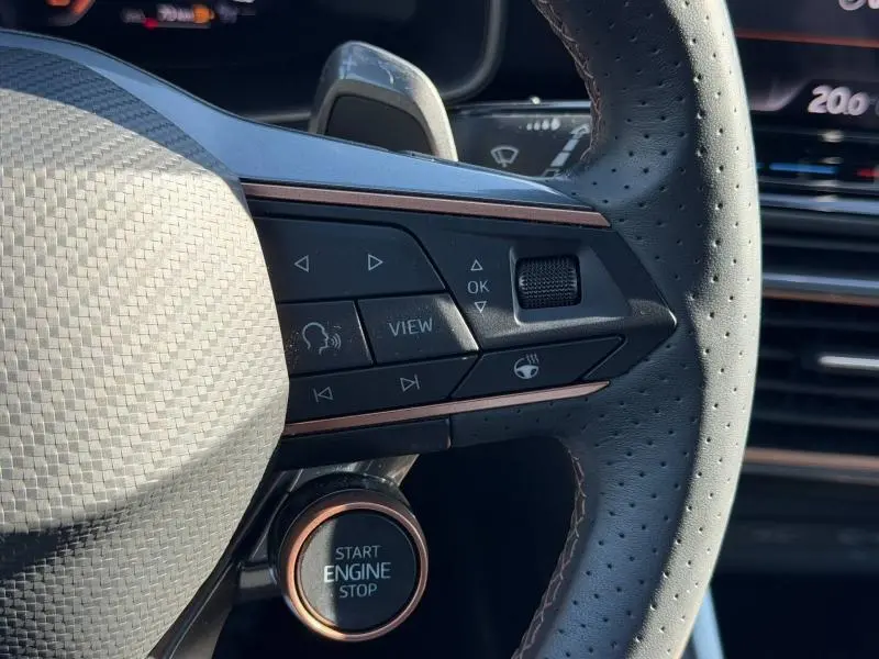 Gros plan sur le volant perforé et le bouton Start Engine Stop du CUPRA Formentor 1.5 eTSI Hybrid 2025, intérieur noir.