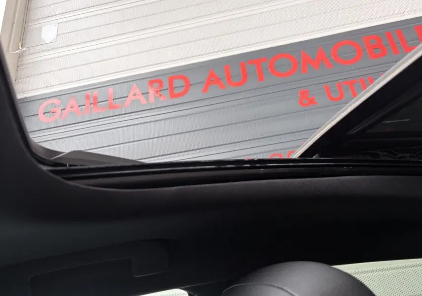Vue intérieure du toit ouvrant ouvert de l’Opel Astra blanc, avec vue partielle sur l’appui-tête noir.