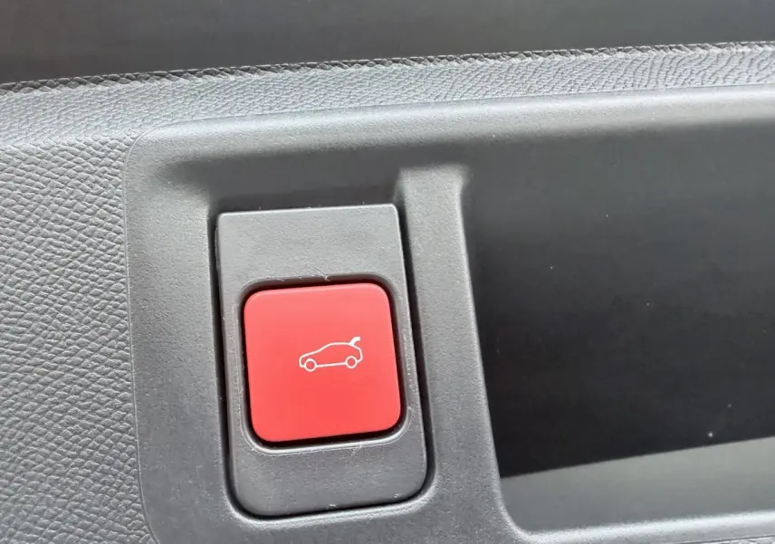 Gros plan sur le bouton rouge d'ouverture du coffre dans l'habitacle de l'Opel Astra 2024.