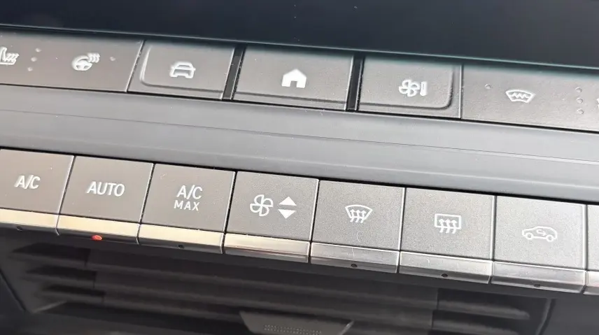 Vue rapprochée du tableau de bord de l’Opel Astra blanc 2024, montrant les commandes climatisation et sièges chauffants.