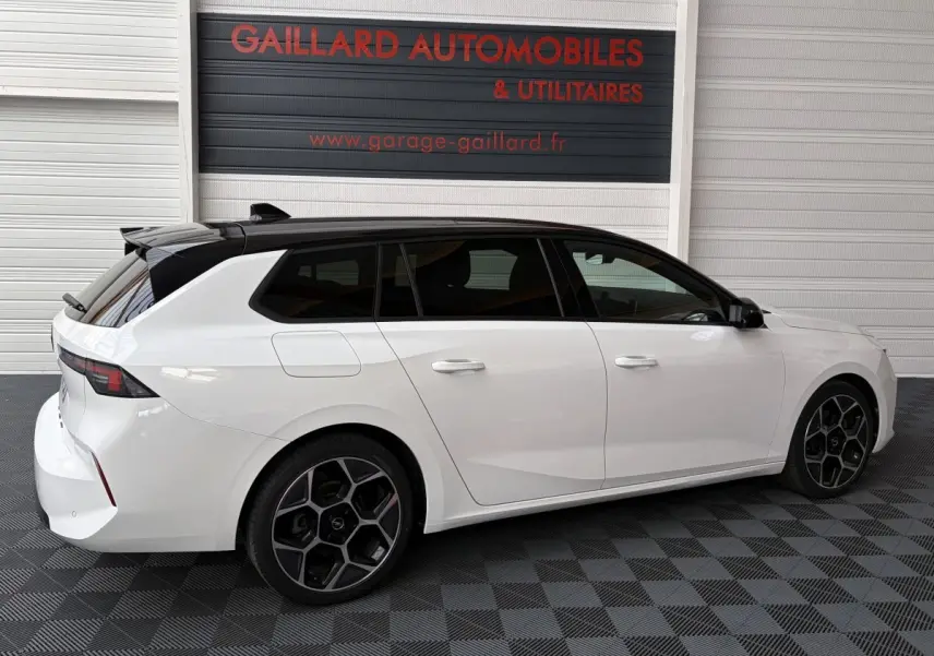 Vue de profil droit d'une Opel Astra blanche break avec toit noir et jantes alliage au design hexagonal.