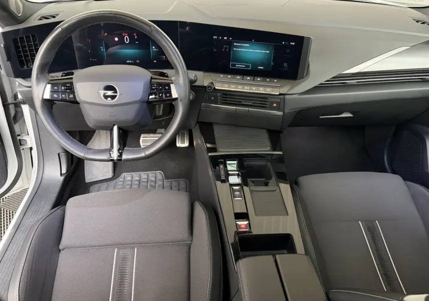 Vue intérieure avant de l’Opel Astra 2024, tableau de bord noir avec écran tactile large et volant multifonctions cuir synthétique.