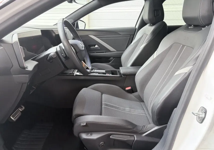 Vue intérieure côté conducteur de l'Opel Astra blanche, avec sièges GS en cuir synthétique et volant multifonctions.