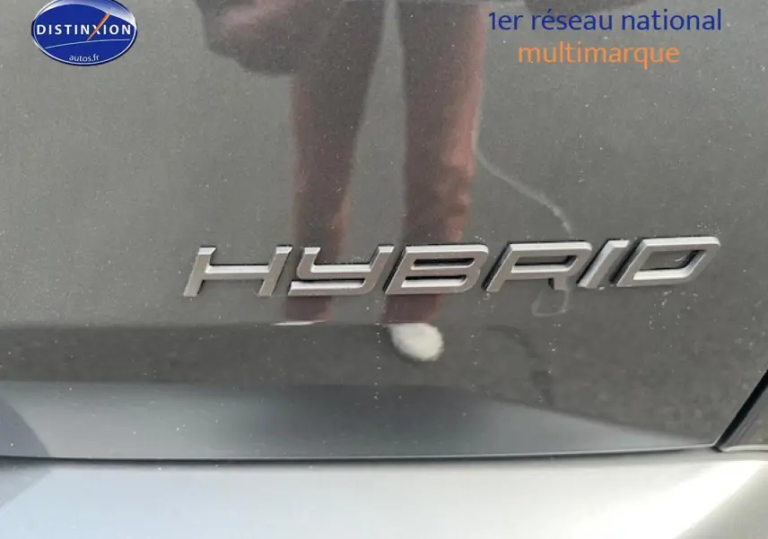 Gros plan sur l’inscription "Hybrid" en chrome sur la carrosserie gris titane d’un Peugeot 3008.