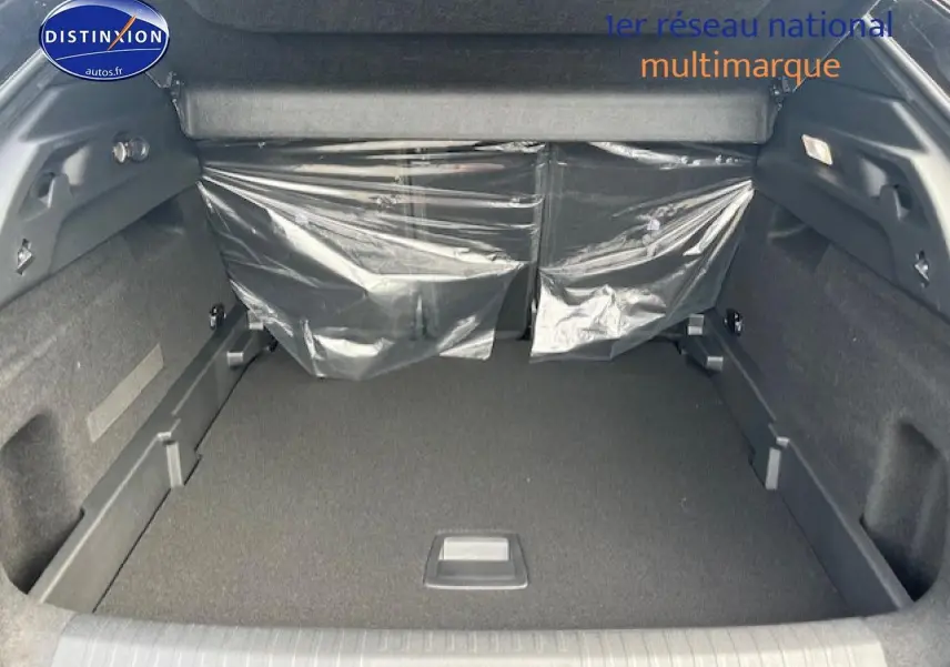 Vue intérieure du coffre spacieux du Peugeot 3008 gris titane, avec banquette arrière protégée par plastique transparent.