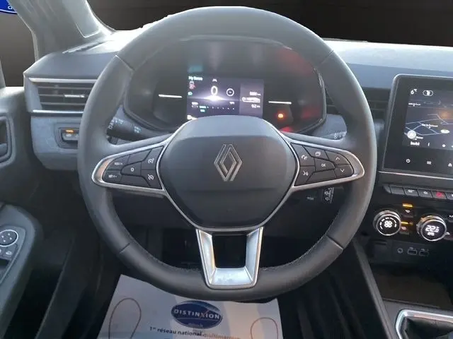 Vue rapprochée du volant cuir synthétique de la Renault Clio gris clair 2025 avec commandes multifonctions et tableau de bord numérique.