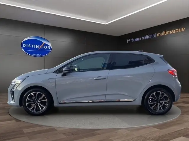 Profil côté gauche d'une Renault Clio Techno TCe 90 gris clair 2025 avec jantes alliage et toit noir en showroom.