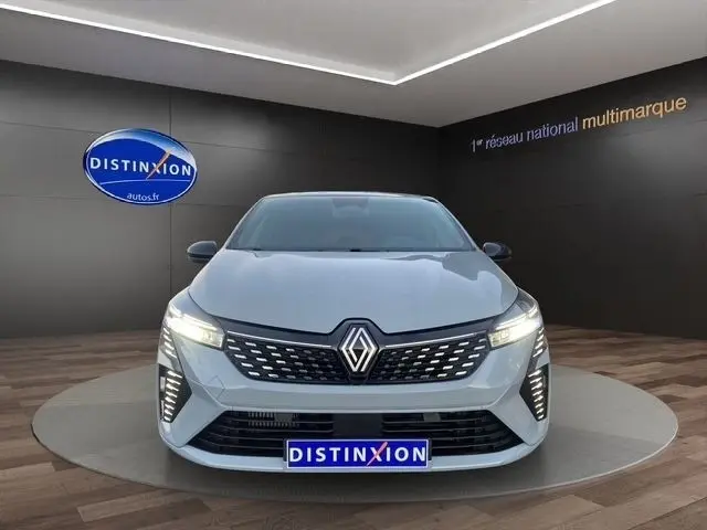 Vue avant d'une Renault Clio Techno TCe 90 gris clair avec phares LED allumés dans un showroom.